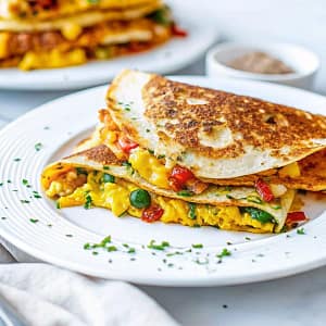 Crispy vegan breakfast quesadillas with tofu scramble and melted cheese on a white plate